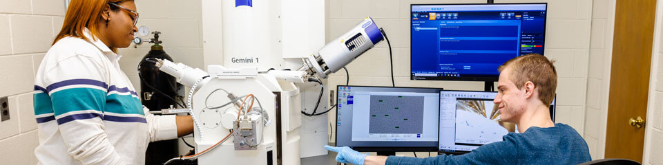 Two Physics students use a sub-nanometer imaging device in the lab.